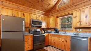 Una cocina tipo cabaña con armarios de madera, refrigerador, microondas, estufa y lavavajillas.