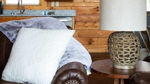 Un salón acogedor con un sofá de cuero, una mesa redonda con una lámpara de fibra natural y muebles de madera.