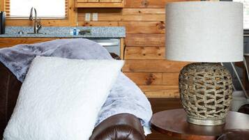 Un salón acogedor con un sofá de cuero, una mesa redonda con una lámpara de fibra natural y muebles de madera.