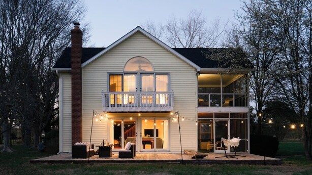 Een tweelaags huis met een balkon, een overdekte veranda en een groot raam.
