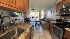 A modern kitchen with granite countertops, stainless steel appliances, and wooden cabinets. - Where Serenity Finds You Kihei Remodeled 1BR Condo Private Lanai and Pool (Kihei)