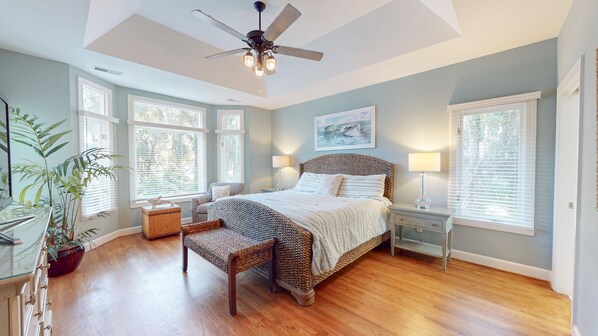 A bedroom with a large bed, a ceiling fan, and multiple windows. - Large Private Home with Private Pool and Spa! (Hilton Head)