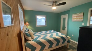 Une chambre à coucher avec un lit, un ventilateur de plafond, une fenêtre et une porte.