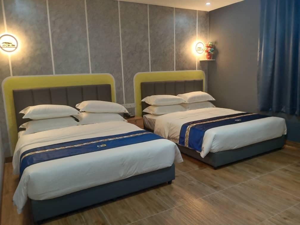 A hotel room with two beds, each with a headboard and pillows.