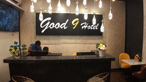 A reception desk with a "Good 9 Hotel" sign, a TV screen, and a floral arrangement. - Good 9 Hotel, Cahaya Kota Puteri (Masai)