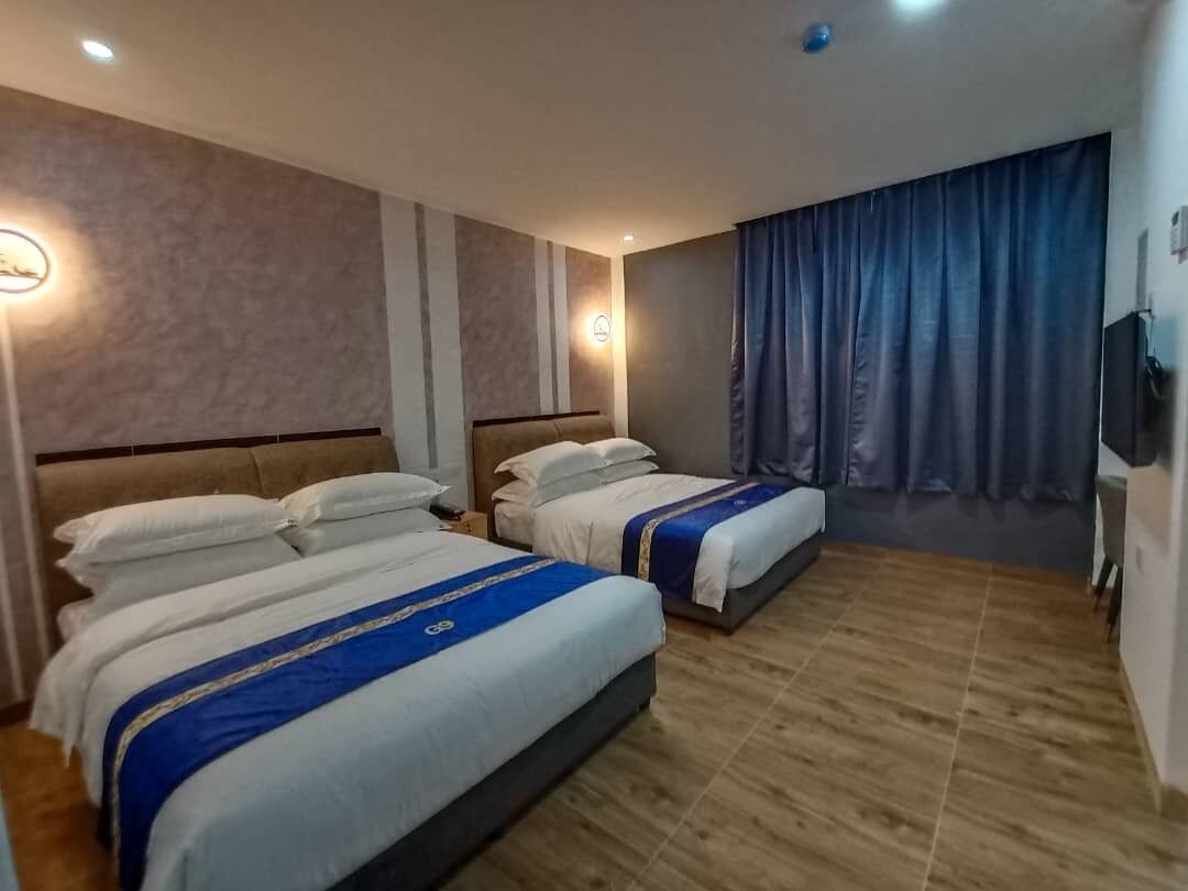 Habitación de hotel con dos camas, suelo de madera y un ventanal con cortinas.