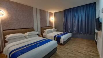 Habitación de hotel con dos camas, suelo de madera y un ventanal con cortinas.