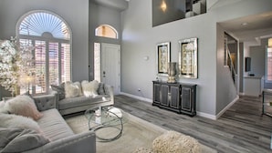 A spacious living room with a grey sofa, a glass coffee table, and a large arched window. - On Golf Course! Snowbird Resort Retreat in Mesa (Mesa)