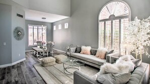 A spacious living room with a grey sofa, a glass coffee table, and a dining area with chairs and a table. - On Golf Course! Snowbird Resort Retreat in Mesa (Mesa)