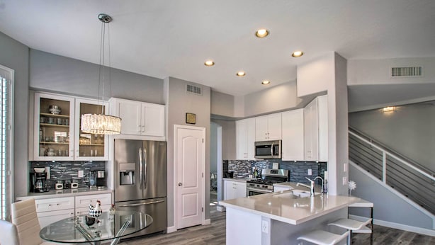 A modern kitchen with a glass dining table, stainless steel appliances, and a central island with bar stools. - On Golf Course! Snowbird Resort Retreat in Mesa (Mesa)