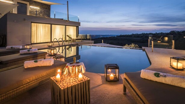 A modern infinity pool with a view of the landscape, outdoor seating with cushions, and candles creating a serene ambiance. - Villa Fortezza - pool, sauna, Jacuzzi and countryside views by MyWaycation (Buje)