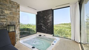 A modern bathroom with a large bathtub, a stone wall, and a view of a lush landscape. - Villa Fortezza - pool, sauna, Jacuzzi and countryside views by MyWaycation (Buje)