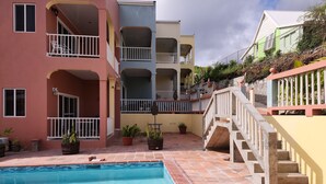 A swimming pool with a tiled deck, surrounded by multi-story buildings with balconies and railings. - The Best of Home - Tranquil, Comfort & Convenient (Beausejour)