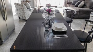 A modern kitchen with a dining table set for four, a sofa, and a TV mounted on the wall. - The Best of Home - Tranquil, Comfort & Convenient (Beausejour)
