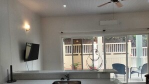 Une cuisine dotée d’un grand îlot central, d’un évier intégré, d’un ventilateur de plafond et d’un téléviseur fixé au mur.