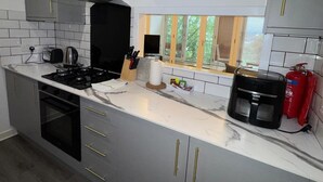 Una cocina moderna con armarios grises, una estufa negra y una cafetera.
