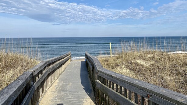 A wooden boardwalk leading to a beach with a clear sky and ocean in the background. - OBX Sunset Lovers ! 2 Bed/2 Bath Soundside Condo with Canal View (Kill Devil Hills)