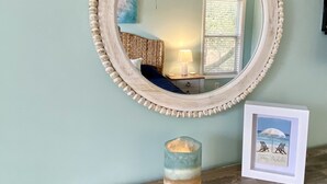 A mirror with a beaded frame, a candle holder, and a framed picture on a wooden surface. - OBX Sunset Lovers ! 2 Bed/2 Bath Soundside Condo with Canal View (Kill Devil Hills)