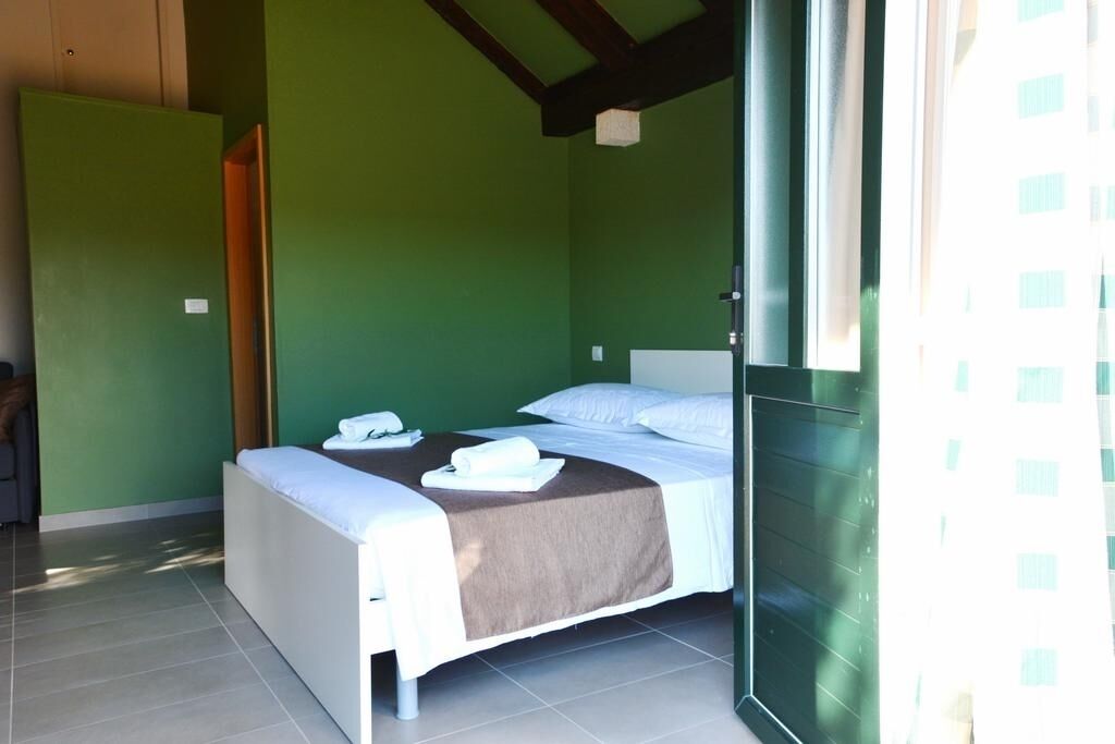 A room with two beds, a green wall, and a window.