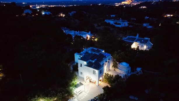 Vista aérea de una zona residencial con varias casas, una piscina y un patio bien iluminado.