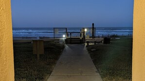 A pathway leading to a beach with a fence and benches. - Beachfront Condominium with Private Beach Access and Heated Pool (South Padre Island)