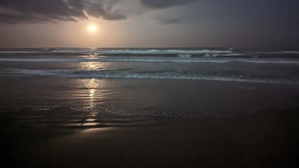 A beach scene with waves and a sun setting or rising in the background. - Beachfront Condominium with Private Beach Access and Heated Pool (South Padre Island)