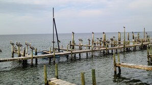 A wooden pier extending into calm waters with several birds perched on the posts. - Beachfront Condominium with Private Beach Access and Heated Pool (South Padre Island)