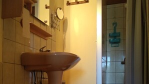 Casa de banho com sanita, lavatório e zona de duche.