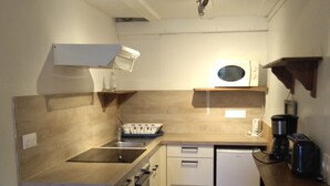 Cozinha compacta com micro-ondas, fogão e pia.