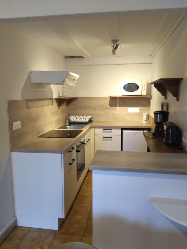 A compact kitchen with a microwave, stove, and sink.