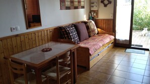 Um quarto acolhedor com uma mesa de madeira, um banco estofado e piso de azulejos.