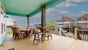 Una terraza de madera con una mesa y sillas, con vistas a una zona residencial con casas de colores.