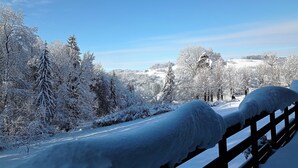 Paisaje nevado con una valla de madera al frente.