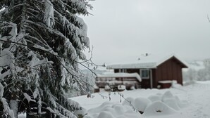 Un paisaje nevado con una cabaña de madera y un árbol cubierto de nieve.