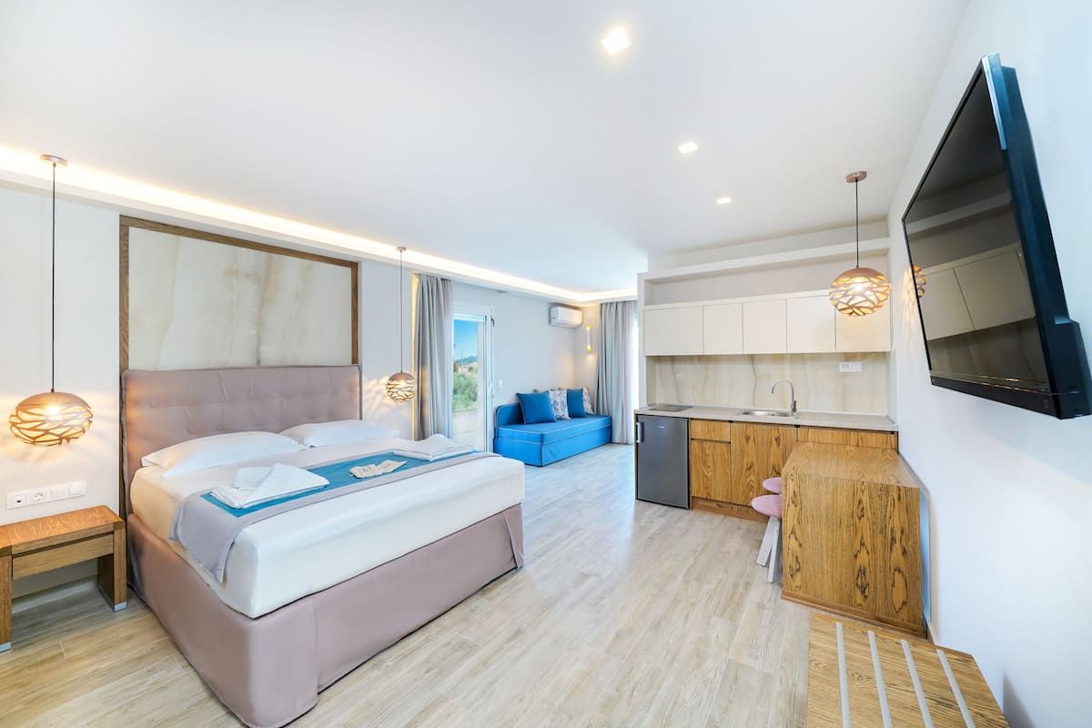 Une chambre d’hôtel moderne dotée d’un grand lit, d’une kitchenette et d’un téléviseur fixé au mur.