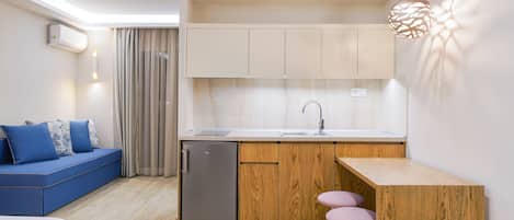 Una cocina compacta con refrigerador empotrado, gabinetes de madera y un pequeño comedor con taburetes.