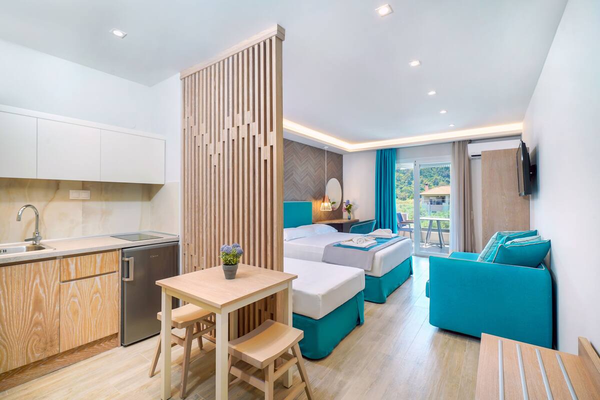 Une chambre d’hôtel moderne dotée d’une kitchenette, d’un coin repas, d’un lit avec vue et d’un canapé.