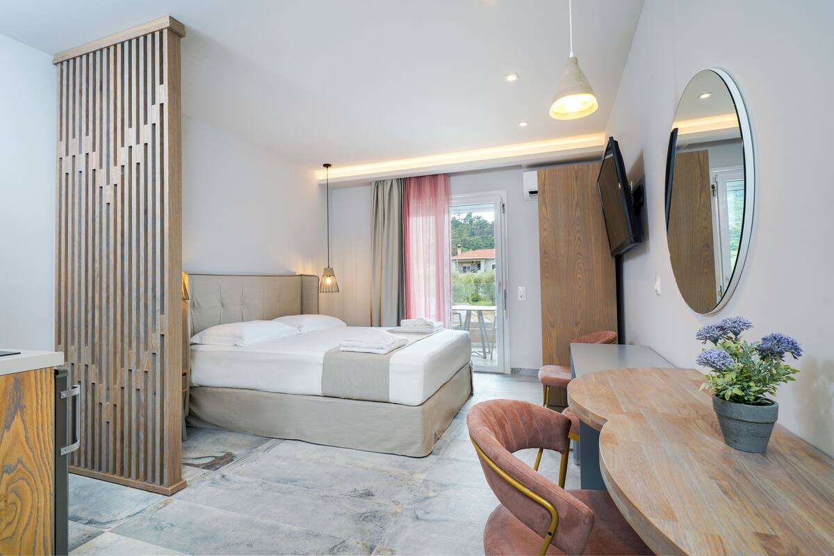 Une chambre d’hôtel moderne équipée d’un lit, d’un bureau, d’une chaise, d’une plante en pot et d’un grand miroir.