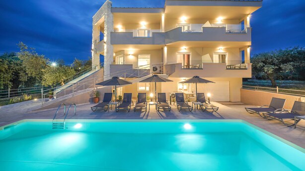 A multi-story hotel with a swimming pool, outdoor seating, and a staircase leading to the upper floors.