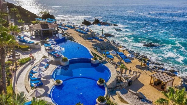 A resort pool area with multiple pools and lounge chairs, surrounded by a beach and ocean view. - Astonishing Studio at Cabo San Lucas (Cabo San Lucas)