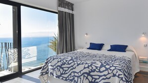 Une chambre moderne avec un grand lit, deux oreillers et une vue sur l’océan.