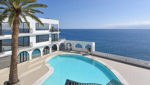 Un bâtiment moderne doté d’une piscine et offrant une vue sur la mer.