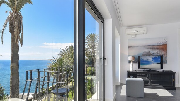 Un salon moderne avec un grand téléviseur, un tableau et une vue sur la mer.