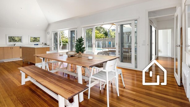 Een ruime keuken met houten kastjes, een grote eettafel en uitzicht op de omgeving via schuifdeuren.