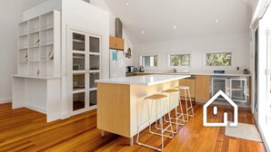 Een moderne keuken met een centraal eiland, barkrukken en inbouwplanken.