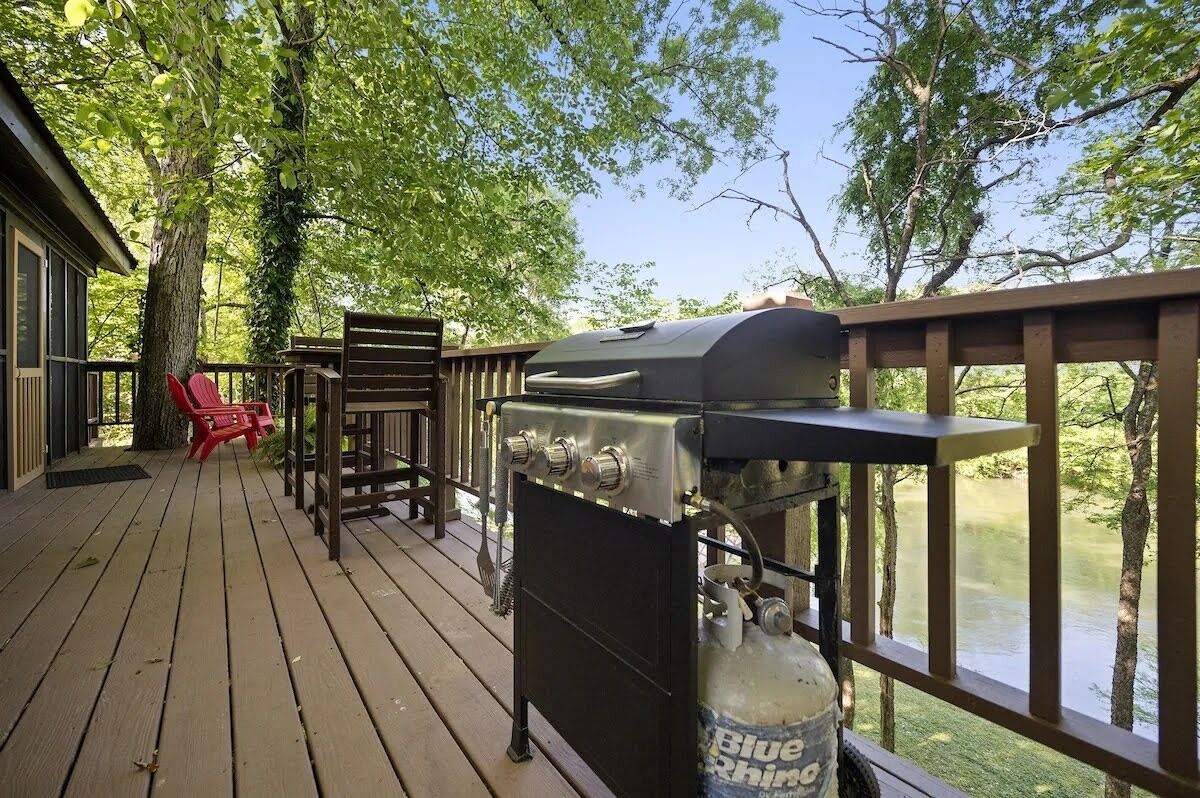 Une terrasse en bois avec un barbecue et une chaise rouge.