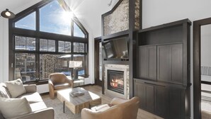 Un salon moderne doté d’une cheminée, de grandes fenêtres et d’un coin salon confortable.