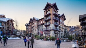 Un immeuble à plusieurs étages conçu dans le style d’un chalet de ski, doté de balcons et d’une façade en pierre.
