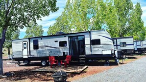 A motorhome with a covered front area, a side door, and a small window. - Grand Canyon RV Glamping Luxury Suite (Glamping Getaway) (Williams)