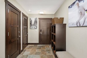 A hallway with wooden doors, a tiled floor, a wall-mounted picture, and a wooden cabinet. - Hayden Lodge by iTrip Aspen Snowmass (Snowmass Village)